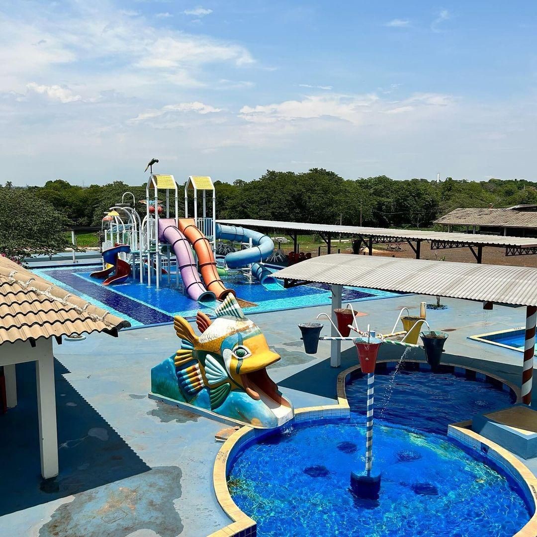 Colorful water park with slides and a fish-themed water feature on a sunny day.