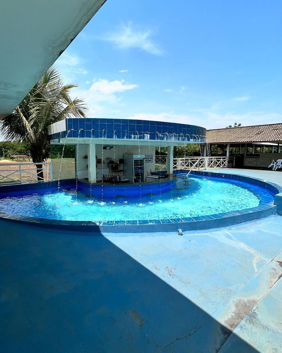 Pessoas relaxando em um bar molhado, desfrutando de bebidas refrescantes dentro da piscina. O bar está localizado em um ambiente descontraído e oferece drinks e sucos enquanto os visitantes aproveitam o lazer.